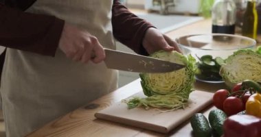 Beyaz kadınların elleri ahşap kesme tahtasında ustalıkla taze lahana dilimler. Ritmik hareket ve hassasiyet gösterisi aşçılık uzmanlığı ve tutku.