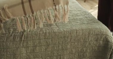 Sakin yatak odasında rahat pijamalı, beyaz bir kadın. Kolayca ve zarafetle yatağa yaklaşıyor, çarşafları dikkatlice örtüyor ve yastıkları düzenliyor..