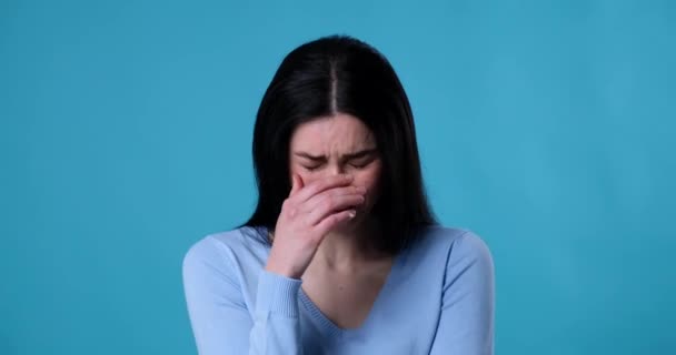 白人女性は青い背景を背景に立っており 孤独の中で苦い涙を流している 悲しい表情で涙を流し 深い悲しみと痛みを表現する — ストック動画