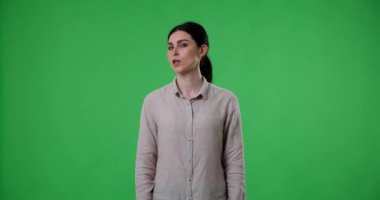 Beyaz bir kadın yeşil perde arkasında duruyor, kafasını sallıyor ve hayır diyor. Herhangi bir projede olumsuz duygular, anlaşmazlıklar veya reddetme iletiliyor.