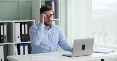 Ofiste sakallı ve gözlüklü bir yönetici bilgisayarda çalışıyor ve hata yaptığını fark ediyor. Gözlüklerini çıkardı, gözlerini ovuşturdu ve çalışmaya devam etti..