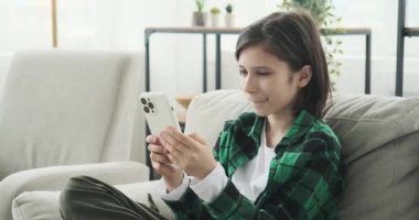 Kanepede oturan genç bir çocuk, kendini cep telefonuna kaptırmış. Dijital medya dünyasına kendini kaptırmış, ya büyüleyici videolara dalmış ya da en sevdiği müziğin melodik melodilerine dalmış..