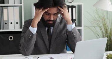 Gözlüklü ve takım elbiseli Hintli bir işadamı ofisinde oturmuş belgeleri inceliyor. Kağıtları incelemeyi bitirdiğinde baş ağrısı belirtileri göstererek şakaklarını ovuyor..