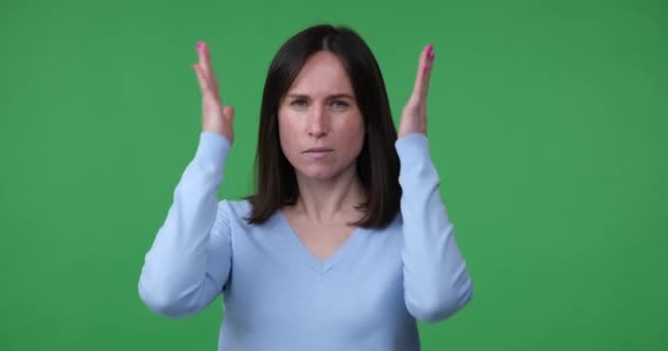 一个高加索女人站在一个绿色的彩色关键背景上 脸上带着严肃的表情 示意我一边用手捂住耳朵 一边什么也听不到 — 图库视频影像