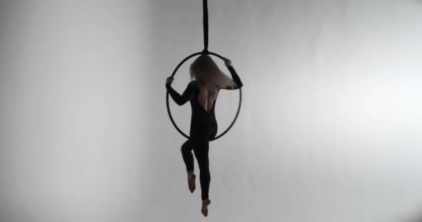 一个自信的白人女人在吊钩上跳舞 在灰色的背景下 她被自己优雅的动作迷住了 穿着光滑的黑色连衣裙 光着脚 — 图库视频影像