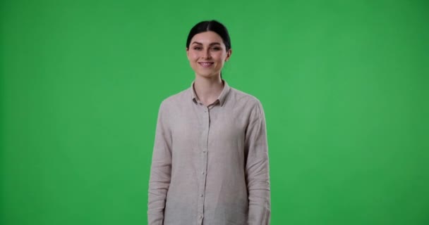 Λευκή Γυναίκα Στέκεται Μια Πράσινη Οθόνη Κοιτάζοντας Κατευθείαν Στην Κάμερα — Αρχείο Βίντεο