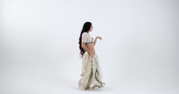 緑と白のサリーで美しいインド舞踊を披露する若いインドの女性 彼女の動きは彼女の服装の豊かな色で補完します 彼女のパフォーマンスはインド文化遺産のお祝いです — ストック動画