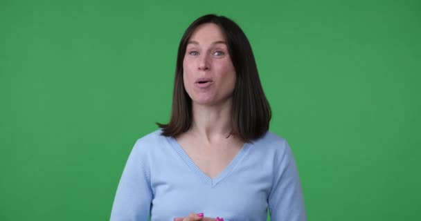 一个自信的白人女人站在绿色的屏幕背景上 说话和做着活泼的手势 她是一名视频博客作者 与网上受众分享她的想法和想法 — 图库视频影像