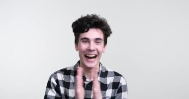 Beyaz arka planda kıvırcık saçlı beyaz bir adam bulaşıcı bir coşku saçıyor. Yüzünü aydınlatan geniş bir gülümsemeyle coşkulu bir alkış yağmuruna tutuldu..