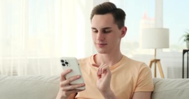 Neşeli bir beyaz adam evinin rahatlığından gelen bir video çağrısına bağlanıyor. Samimi bir koltukta otururken, telefonunu ışıltılı bir gülümsemeyle tutuyor, sıcaklık ve coşku saçıyor..