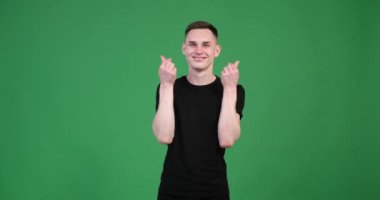 Canlı yeşil bir arka planda, beyaz bir adam ellerini uzatarak parmaklarıyla bir kalp şekli oluşturur. Bu jest sevgiyi, sevgiyi ve şefkati temsil ediyor, sıcaklığını ve şefkatini gösteriyor..