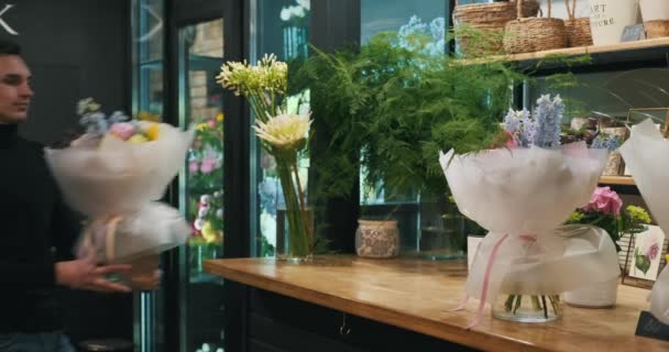 Florista Masculino Talentoso Contra Pano Fundo Uma Loja Flores Vibrante — Vídeo de Stock