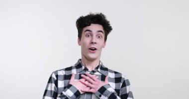 Beyaz arka planda çekici kıvırcık saçlı beyaz bir adam, ayakta duruyor, gözleri şaşkınlık içinde büyüyor ve ağzı 