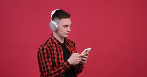 Молодого Чоловіка Червоному Тлі Можна Побачити Занурившись Його Телефон Насолоджуючись — стокове відео
