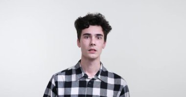 Saf beyaz bir arka plana karşı duran kıvırcık saçlı beyaz bir adam. Gözleri şaşkınlıkla açıldı ve ürkmüş bir ifade yüzünü kapladı..