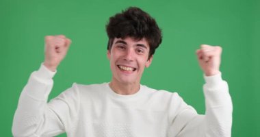 Canlı yeşil bir arka planda saf neşe içinde eğlenen mutlu bir beyaz adam. Yüzü ışıl ışıl bir gülümsemeyle ışıldıyor ve mutluluğu ifade ederken gözleri mutlulukla parıldıyor..