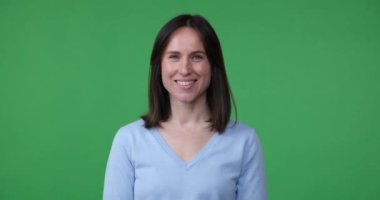 Yeşil ekran arka planında duran beyaz kadın yüzünde bir gülümsemeyle doğrudan kameraya bakıyor. Aniden bir şeye şaşırır ve haykırır: