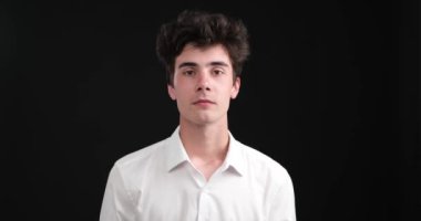 Omuzlarını çarpıcı bir siyah arka plana yaslayan yakışıklı, beyaz bir adam. Kusursuz görünüşü ve kendine güveni ile karşı konulmaz bir cazibe yayıyor..
