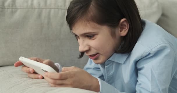 Мальчика Видят Лежащим Диване Поглощенным Мобильной Игрой Лицо Отражает Смесь — стоковое видео