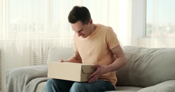 Radostný Muž Obdrží Dlouho Očekávaný Balíček Posadí Útulnou Pohovku Oči — Stock video