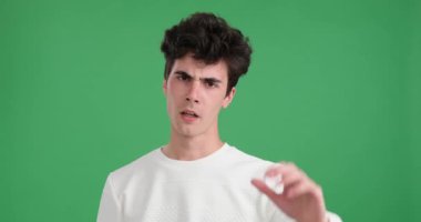 Kendine güvenen ve iddialı beyaz adam canlı yeşil bir arka plana sahip. Avuç içi dışa dönük bir şekilde, net ve kararlı bir dur hareketi yapar..