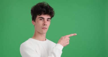 Kafkasyalı bir adam parmağını canlı yeşil bir arka plana doğru doğrultuyor. Kararlı bir ifade ve kasıtlı bir duruş ile dikkatleri belirli bir yöne yönlendirir..