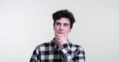 Beyaz arka planda duran beyaz kıvırcık saçlı adam. Kendini derin düşüncelere daldırıyor, geniş bir yelpazede seçenekler düşünüyor ve keşfediyor. Yaralı bir alın ve odaklanmış bir bakışla.