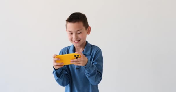 Menino Asiático Jogando Telefone Celular Fundo Branco Com Sorriso Infeccioso — Vídeo de Stock