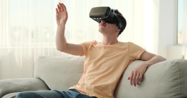 Hombre Guapo Abrazando Mundo Realidad Virtual Mientras Sienta Sofá Sala — Vídeos de Stock