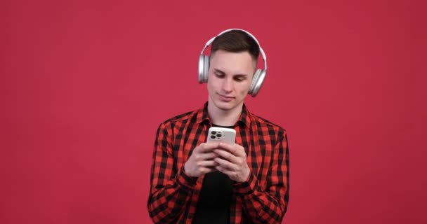 Червоному Тлі Молодий Кавказький Чоловік Насолоджується Своїм Часом Телефоном Руці — стокове відео