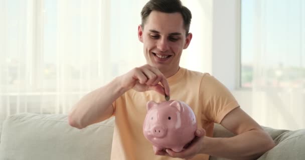 Odhodlaný Muž Investuje Finanční Budoucnosti Uložením Mincí Prasečí Banky Pozorně — Stock video