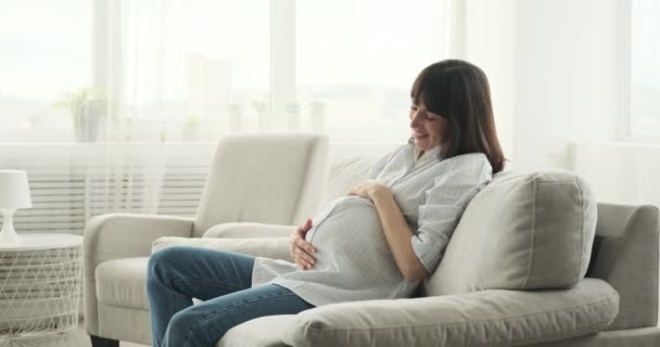 Een Zwangere Vrouw Zit Zitbank Haar Gezicht Straalt Van Vreugde — Stockvideo