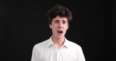 Siyah arka planda esneyen yorgun beyaz bir adam. Yüzünde yorgunluk belirtileri var, gözleri sarkmış, ağzı sonuna kadar açık ve elleri esnemiş..