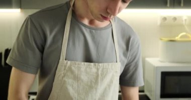 Kaşıkla hamuru kaseye karıştıran bir adamın portresi. Odaklanmış ifadesiyle ve ellerinin karmaşık hareketleriyle, mükemmel bir hamur yaratmak için bileşenleri zahmetsizce birleştiriyor..