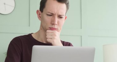 Sessiz ve düzenli bir çalışma alanında, düşünceli bir adam işe dalmış, dizüstü bilgisayara odaklanmış. İçsel ifadesi, görevlerini titizlikle yerine getirirken derin bir konsantrasyon gösterdiğini gösteriyor..