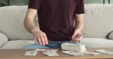 Kafkasyalı adam oturma odasındaki kanepede oturur, nakit para saymaya dalmıştır. Kararlı ifadesi, parayı idare etme konusundaki ciddi yaklaşımını gösteriyor.