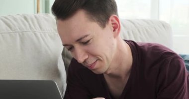 Gülümseyen beyaz bir adamın neşeli ve canlı portresi bilgisayarında mesajlaşırken yakalandı. Parlak gülüşü, dostça sohbete dalarken sıcaklık ve pozitiflik saçıyor..