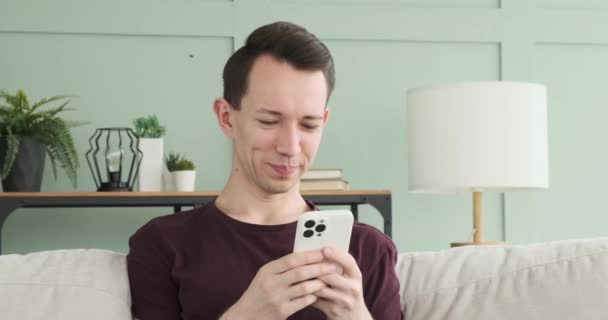 Młody Mężczyzna Siedzi Kanapie Śmiejąc Się Pisząc Przez Telefon Jego — Wideo stockowe