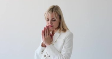 Düşünceli kadın temiz beyaz bir arka planda görünür, derin düşünce ve yansıma içinde. Düşünceli ifadesi ve odaklanmış bakışları, iç gözlem ile olan ilgisini gösteriyor..