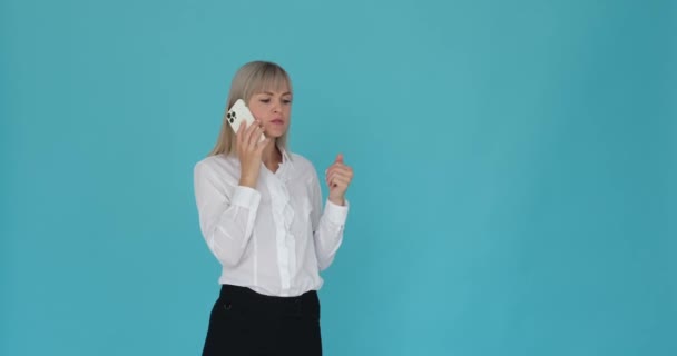 真剣なビジネスウーマンは 穏やかな青い背景の電話会話に従事していることが示されています 彼女の焦点を当てた表現とプロのメカニズムは 呼び出しの重要性を示しています — ストック動画