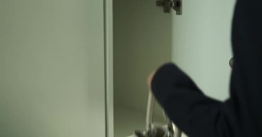 Kadın bir depo dolabını açar ve çantasını dikkatlice içine yerleştirir, yakın çekim sırasında yakalanır. Hassas ve kasıtlı hareketlerle eşyalarının güvenli bir şekilde depolandığından emin olur..