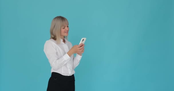 Kadının Telefonuna Göz Gezdiriliyor Dingin Mavi Arka Planda Kahkahalarla Gülüyor — Stok video