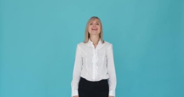 Düz mavi bir arka plana evet diyerek anlaşmayı ifade eden bir kadın. Olumlu ifadesi ve kafa sallama hareketi onayını ya da onayını gösteriyor..