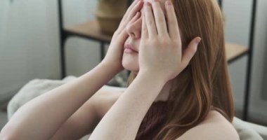 Kızıl saçlı genç bir kız görünür bir şekilde üzgün ve sıkıntılı bir ifadeyle bir kanepede oturuyor. Kanepenin bastırılmış ışıklandırması ve mahrem ortamı kızların duygularına dikkat çekiyor..