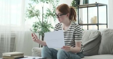 Genç bir kız gazetelerle uğraşırken ve video görüşmesi yaparken gülerken yakalandı. Bulaşıcı gülüşü ve parlak ifadesi o anki neşesini yansıtıyor..