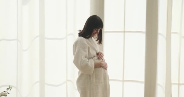 Gravid Vit Kvinna Ses Försiktigt Smeka Magen Nära Fönstret Hennes — Stockvideo