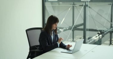 Bilgisayarda çalışan başarılı bir kadının mutluluğu ve memnuniyeti. Zafer anında, arkasına yaslanır, neşe ve gururla ışıldar. Adanmışlığı ve sıkı çalışması meyvesini verdi..