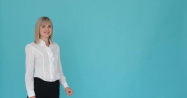 İş kadını, sakin mavi bir arka planda el kol hareketi yapıp sağa işaret ederken görülüyor. Mesleki tavrı ve el hareketi ilginç bir şey gösterdiğini gösteriyor..