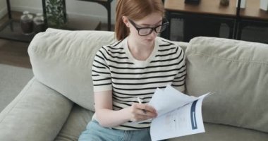 Genç bir kız kanepede otururken kağıtlara not tutarken yakalanır. Düşünceli bir ifadeyle, önemli bilgileri ya da fikirleri dikkatlice yazar..