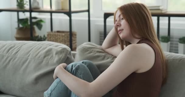 Melancólica Adolescente Caucásica Representa Sentado Sofá Expresión Pensativa Transmite Una — Vídeos de Stock